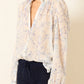 a sheer, long-sleeve button-up blouse by Alix Of Bohemia with a delicate blue and beige floral pattern