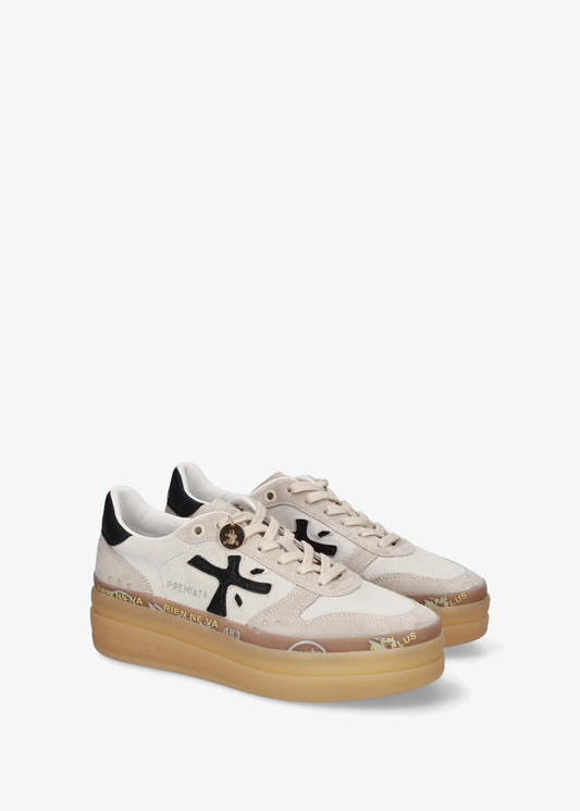 A low-top platform sneaker by Premiata, featuring a cream and beige suede and mesh upper, a black cross logo on the side, gold-tone hardware, and a thick tan gum sole.